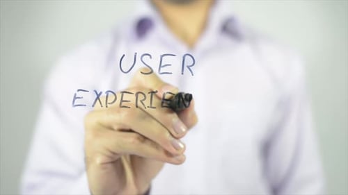 Person Writes User Experience on Glass Surface