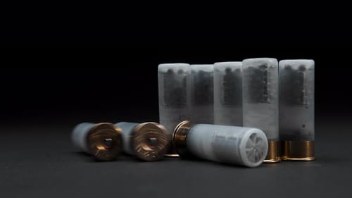 Close-up: Shotgun shells are on the table against a dark background, one cartridge is rolled