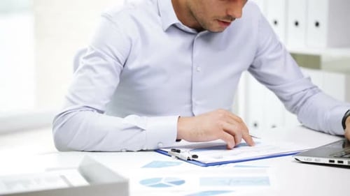 Man Reviews Charts and Graphs in Bright Office