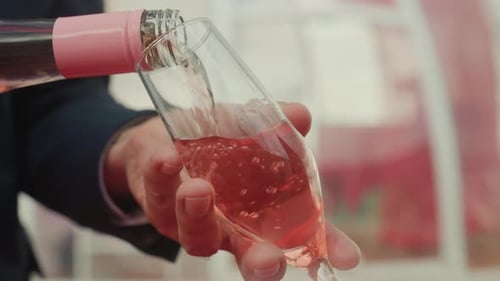 Man Pouring Pink Champagne into a Glass