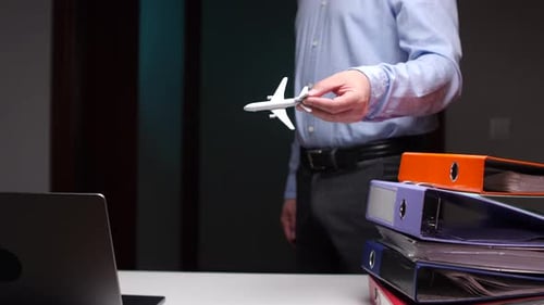 Businessman Holding Model Airplane in Office Setting