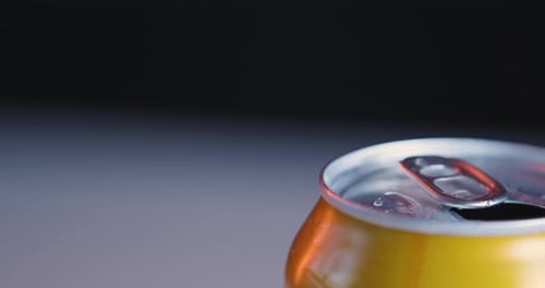 Lata de refresco amarilla con agua condensada, cámara panorámica, primer plano