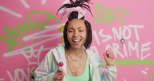 Woman Dances with Lollipop Against Graffiti Wall