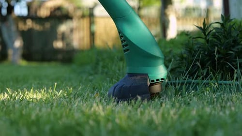 Worker Mowing Fresh Green Grass in the Garden with His Hand Lawn Mower Trimmer Gardener Pruning a