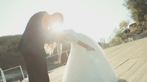 Couple de mariés s'embrassant romantiquement sur fond de soleil éclatant