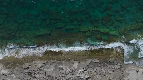 Aerial Video of a Rocky Beach With Waves Gently Washing Over the Stones Creating a Beautiful