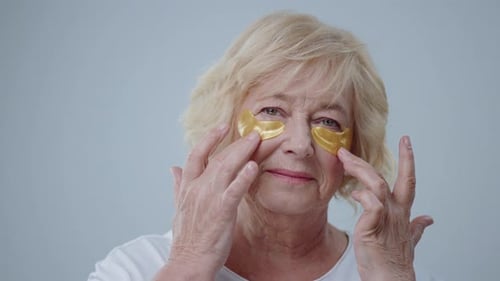 Senior Woman Applying Golden Eye Patches