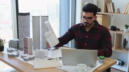 Indian Architect Designing Modern City Model in Office Setting