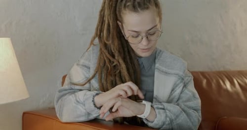 Woman Using Smartwatch on Couch Inside Home