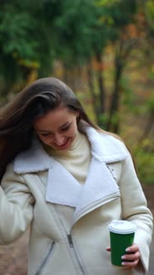Pretty lady walking by in autumn street. Attractive young woman walking down the park.