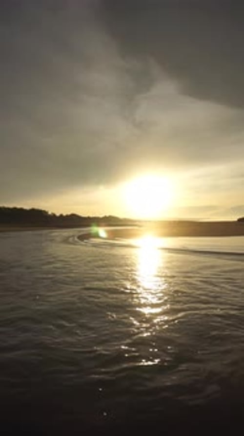 belle vue vidéo verticale du lever du soleil sur la plage avec de petites vagues, panorama naturel matinal