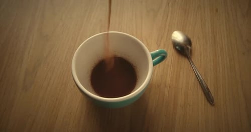 Pouring Instant Coffee into a Blue Cup
