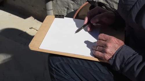 Closeup of an artist's hand drawing a landscape on the street