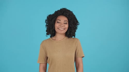 Front View of Attractive African American Woman Smiling to Camera Isolated on Blue Background