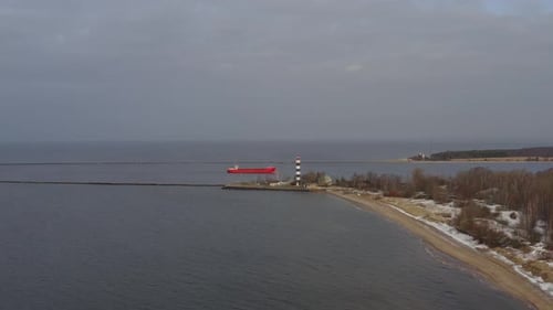 Aerial view of container ship comming into the port. Light house in foreground.