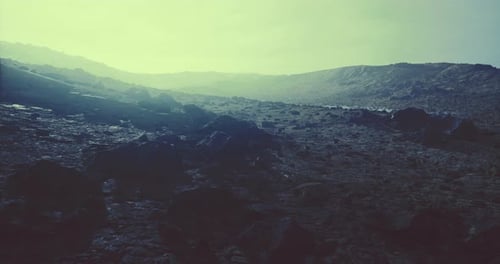 Dramatic Landscape with Rocky Terrain Under a Hazy Sky at Dusk