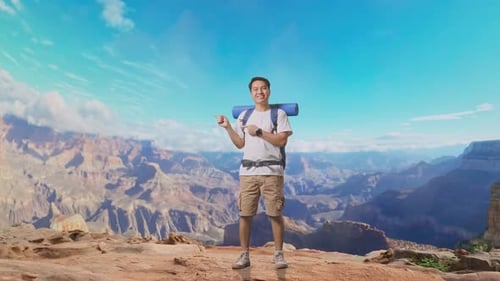 Asian Male Smiling And Pointing To Side At The Top of Mountain