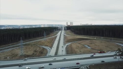 Highway Traffic Crossing a Bridge Near a Forest and a City in the Distance