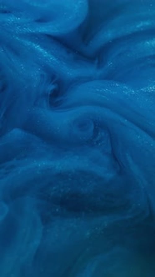 Abstract Bright Blue Paint Swirling Underwater in a Vertical