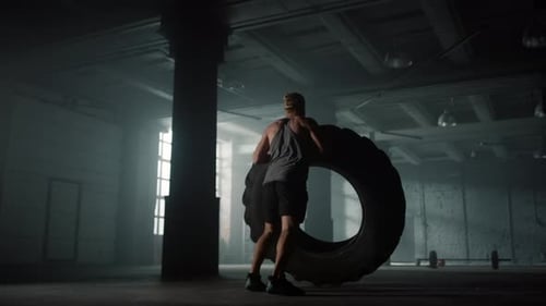 Male Athlete Preparing for Strength Exercise with Rubber Tire. Back View Strong