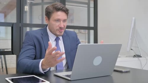 Enthusiastic Businessman on Video Call in Modern Office