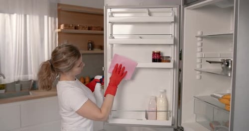 Woman Cleaning Refrigerator Door in Modern Kitchen