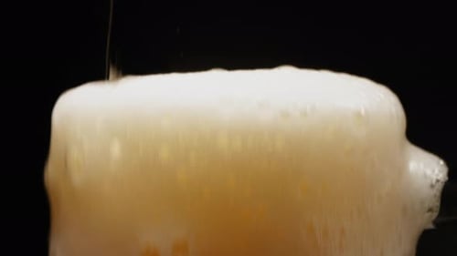Beer Pouring into a Mug, Overflowing with Foam