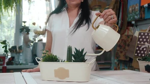 Caring Woman Florist Watering Pouring Green Plants on Table in Flower Shop