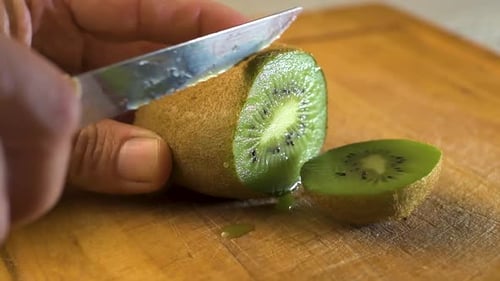 Cutting delicious kiwi slices on a wooden board. Close up. Kiwi fruit. Vitamin.