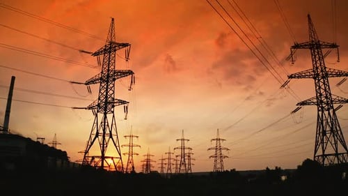 Electricity Pylons Silhouetted Against Fiery Orange Sunset