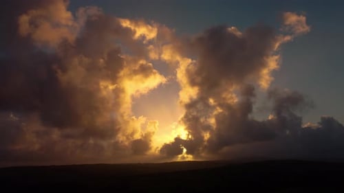 Lapso de tiempo al amanecer con la salida del sol y la luz de Godray atravesando las nubes oscuras de las colinas