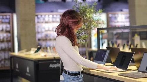 Una mujer trabaja con su portátil en una tienda destacando la multitarea moderna