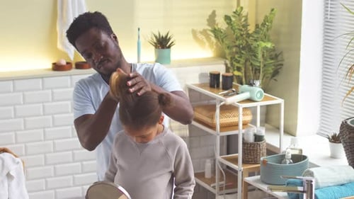 Man Brushing Child's Hair in Bathroom