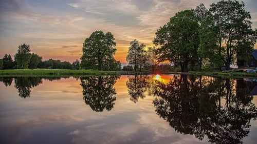 Sunset across the lake with the colorful sky reflecting off the mirror-like surface of the water - t