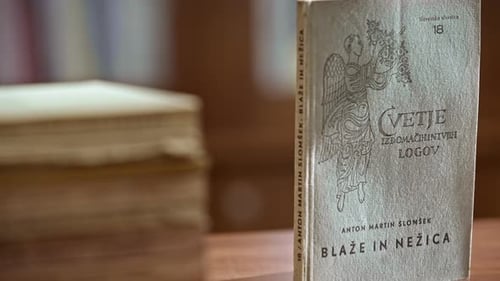 Close up of an book with the title Blaže in Nežica in the background in blur is a pile of books.