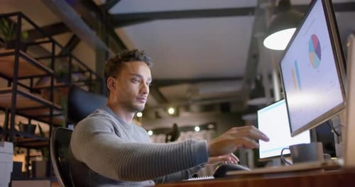 Zweirassiger Geschäftsmann, der nachts im Büro am Schreibtisch sitzt und Computer benutzt, Zeitlupe