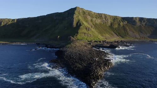 Ascending aerial tilt down revealing the shape of the Grand Causeway's hexagonal basalt formation