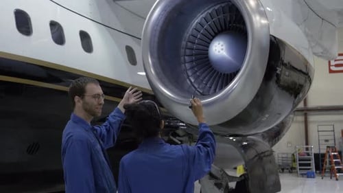 Mecánicos inspeccionando el motor de un avión en Hangar Adult