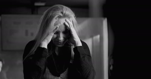 Businesswoman in black and white photo holding head in hands, overwhelmed by stress