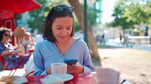 Pretty Woman Sitting Outdoors Cafeteria Use Smartphone Chatting with Friends