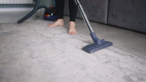 Adult Vacuuming Carpet Indoors Barefoot