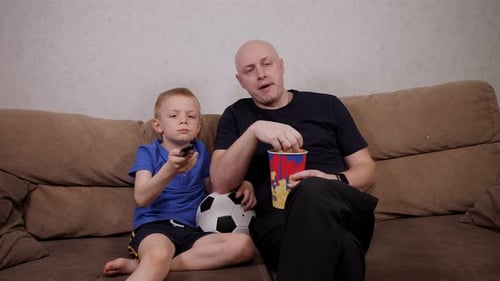Father and Son Relaxing at Home with TV