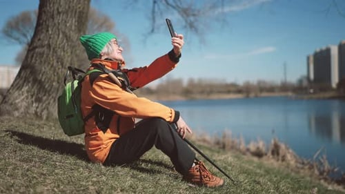 Aged Woman Traveler Resting After Walk in City Park and Taking Selfie By Phone Active Lifestyle in