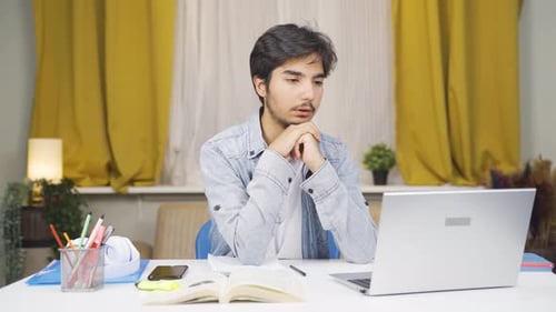 Young Man Concentrating on Laptop at Desk