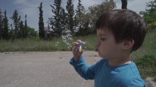 Kid plays withe a bubble blowing toy SLOW MOTION