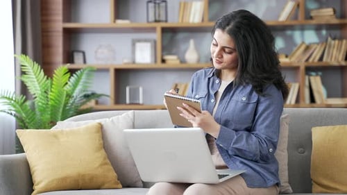 Woman with Laptop Taking Notes at Home