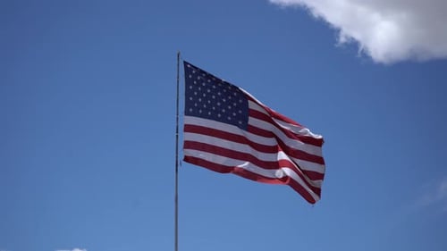 American Flag Waving Against Blue Sky Background