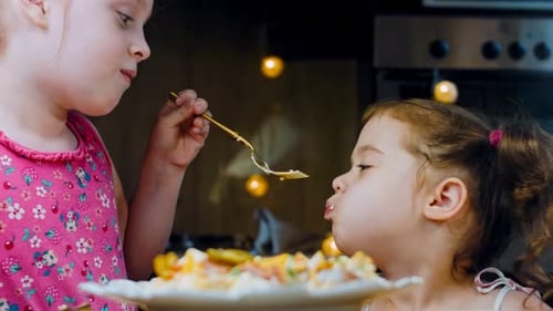 Dos niñas pequeñas prueban cuidadosamente la ensalada