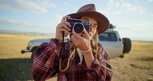 Photographer Taking Pictures with Vintage Camera in a Field at Sunset