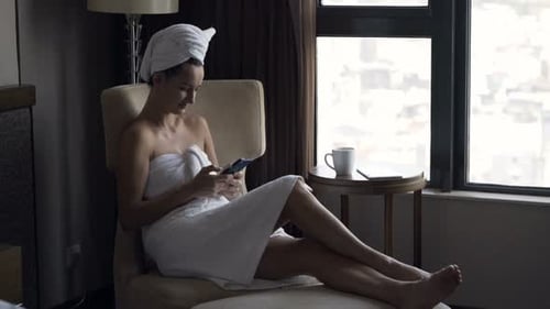 Woman in Towel Using Phone in Hotel Room